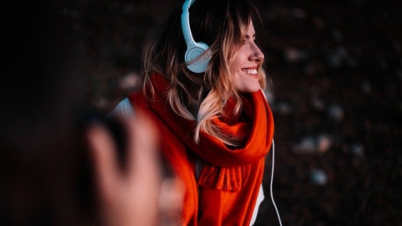 Frau hört lächelnd Musik über Kopfhörer 