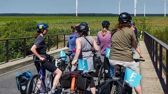 Radlerinnen auf einer Brücke in der Landschaft