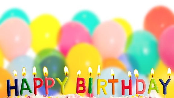 Bunte Buchstabenkerzen bilden den Schriftzug "Happy Birthday" auf einem Geburtstagskuchen.