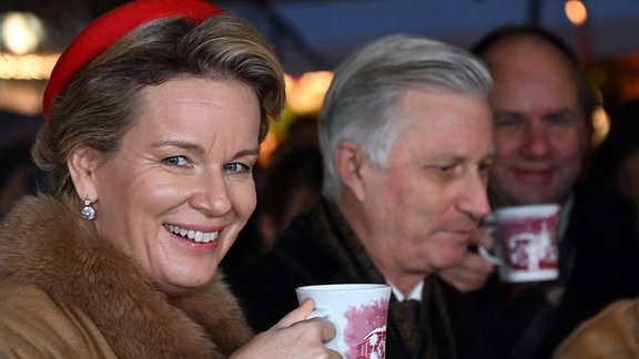 König Philippe und Königin Mathilde von Belgien trinken auf dem Weihnachtsmarkt auf dem Neumarkt Glühwein.