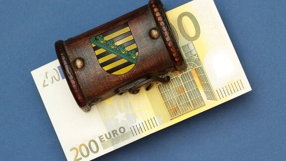 Bündel 200 Euro Geldscheine liegen in einer Schatztruhe mit Landeswappen des Flächenlands Sachsen