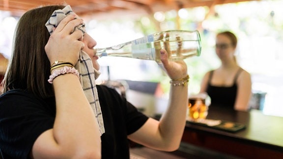 Eine Frau trinkt aus einer Flasche Wasser.