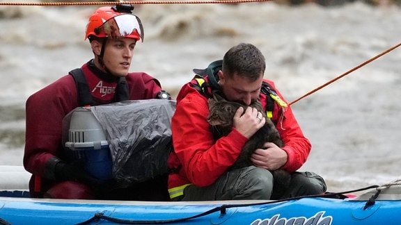 Ein Bewohner mit seiner Katze wird mit einem Schlauchboot aus seinem überfluteten Haus evakuiert.