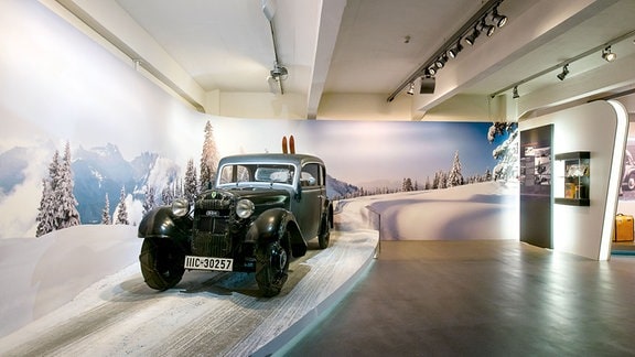 Blick ins August Horch Museum in Zwickau: ein Oldtimer sumgeben von einer Dekoration, die einer Scheelandschaft gleicht