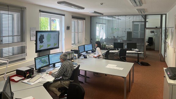 Landeshochwasserzentrale - Ein großer Raum mit zahlreichen Computerbildschirmen, an denen Menschen arbeiten.