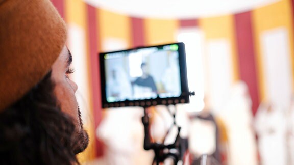 Ein Kameramann schaut beim Filmen auf seinen Monitor