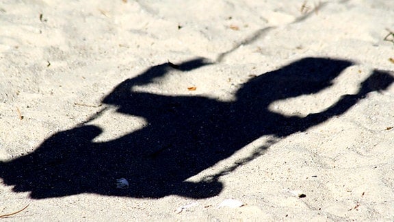 Schatten eines Kindes auf einer Schaukel.