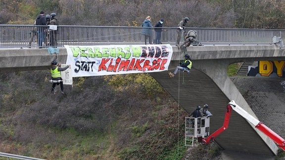 Klimaaktivisten hängen während einer Abseilaktion von einer Brücke über der Autobahn 4 neben einem Transparent mit der Aufschrift "Verkehrswende statt Klimakrise". 