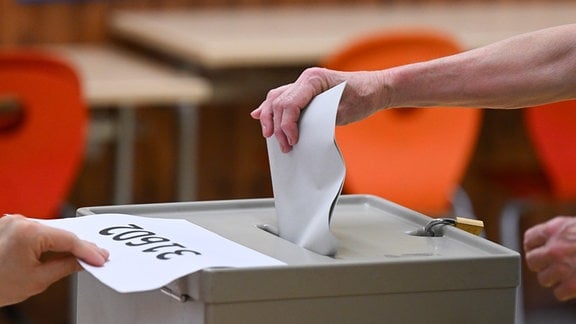Eine Frau wirft bei der Stimmabgabe in einem Wahllokal den Stimmzettel in die Wahlurne