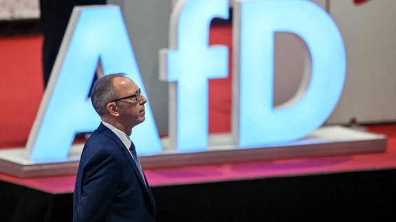 Jörg Urban (AfD), sächsischer Landesvorsitzender, steht vor seiner Rede auf dem Landesparteitag der AfD in der Sachsenlandhalle an dem Logo der Partei.