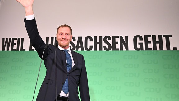 Michael Kretschmer (CDU), amtierender Ministerpräsident von Sachsen und Spitzenkandidat, winkt nach der Verkündung der ersten Hochrechnungen auf der Bühne.