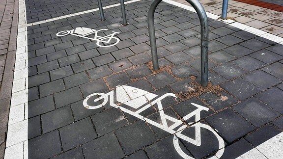 Parkplatz für Lastenräder. Ein auf den Bürgersteig gemaltes Symbol zeigt ein Lastenfahrrad neben einem Befestigungsbügel
