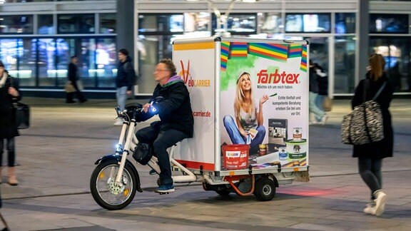 Mann auf einem Lastenrad mit Maler-Werbung