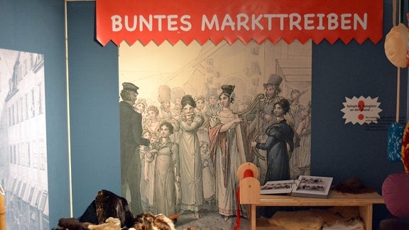 Eine Wand im Kindermuseum Leipzig informiert über das bunte Markttreiben in der Geschichte der Stadt