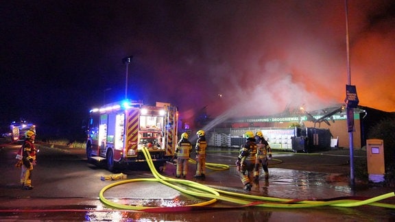 Feuerwehrleute löschen einen brennenden Einkaufsmarkt.