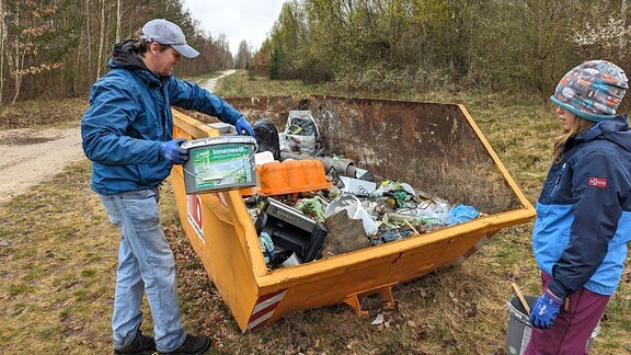 Ein Mann wirft Müll in einen Container. 