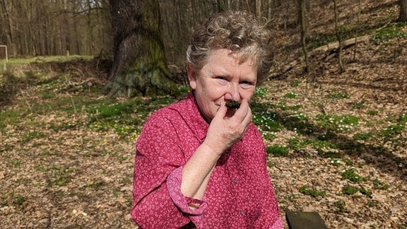 Eine Frau riecht an Moos. 
