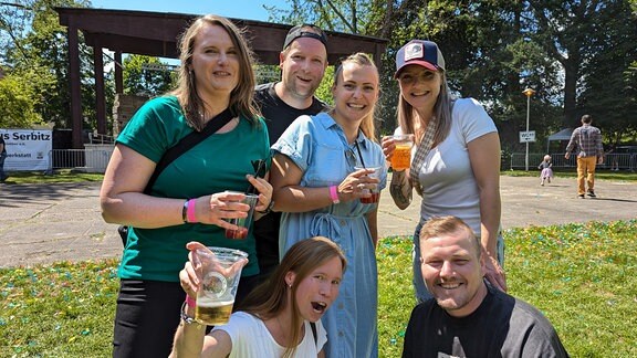 Eine Gruppe von Frauen und Männern lacht in die Kamera. 