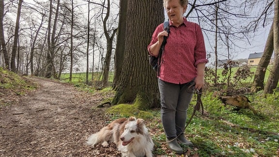Eine Frau und ein Hund in einem Wald.