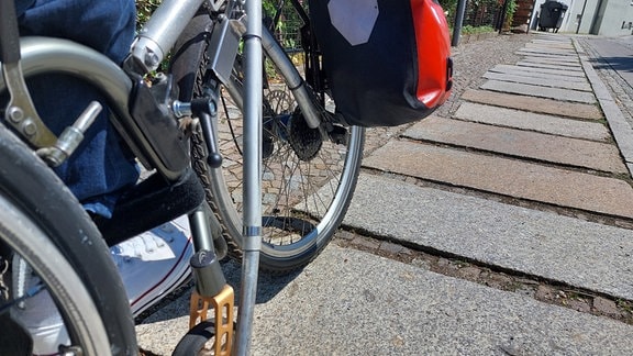 SPD-Stadtratskandidat Christian Gwenner, unterwegs mit dem Handbike, auf einem huckeligen Gehweg in Delitzsch