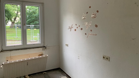 Kaffee-Aufkleber an einer Wand und loser Heizkörper in einer früheren Küche bei Umbaumaßnahmen
