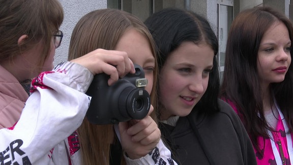 Ein Kind hat einen Fotoapparat vor dem Gesicht 