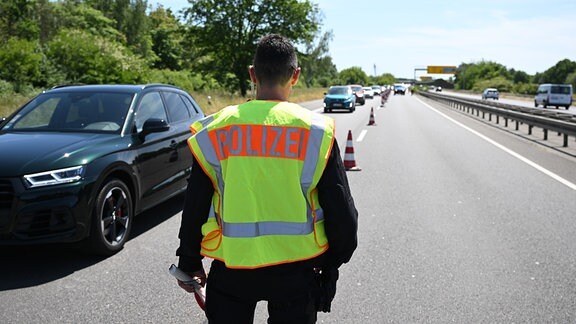 Ein Polizist am Kontrollpunkt Bundesstraße B2 kontrolliert Personen, die in Richtung Innenstadt fahren.