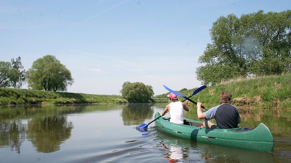 Zwei Personen fahren in einem Kanu auf einem Fluss.