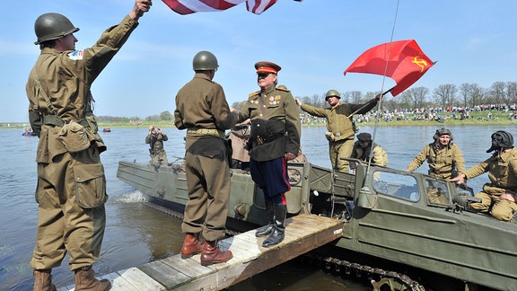 An der Elbe in Torgau stellen Menschen das Zusammentreffen russischer und amerikanischer Truppen von 1945 nach