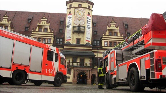 Einsatzwagen der Feuerwehr stehen von einem historischen Gebäude