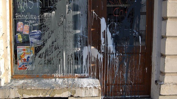 An einem großen Ladenschaufenster und einer Tür ist Farbe und Öl verschmiert worden.