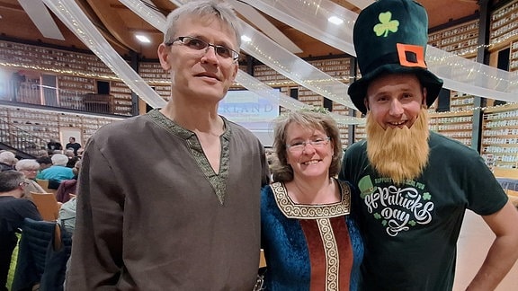 Ein Ehepaar, dass sich m Kostümverleih irisch inspirieren ließ steht neben einem als grüner Kobold verkleideter Mann in der Veranstaltungshalle "O" in Oschatz.