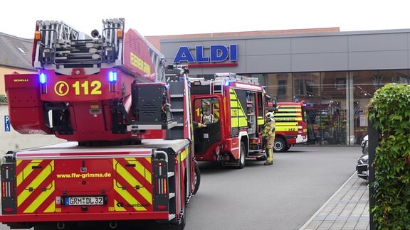 Zwei Feuerwehrfahrzeuge stehen stehen vor einem Supermarkt in Grimma
