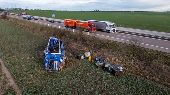 Ein Lkw und einige Fässer liegen neben einer Autobahn.