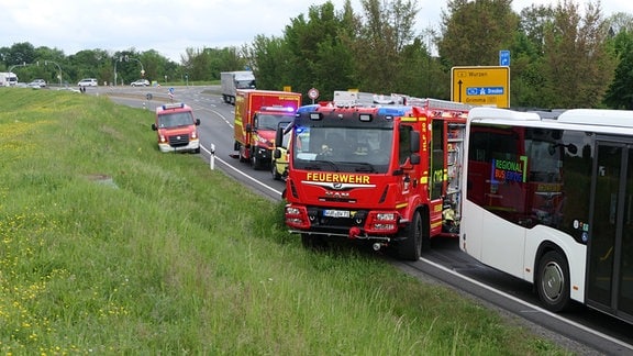 Feuerwehrautos stehen an der Unfallstelle vor einem Bus.
