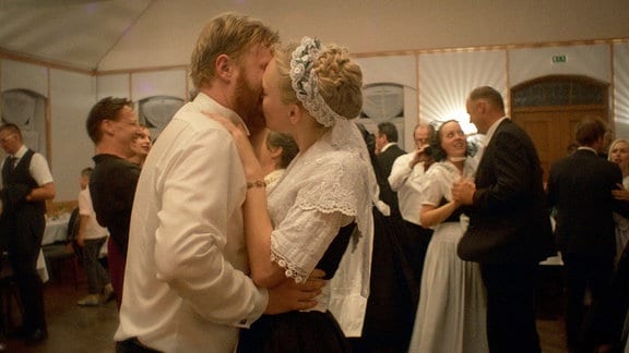 Ein Brautpaar küsst sich bei einer Hochzeitsfeier.