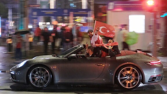 Türkische Fans jubeln von einem Auto heraus.