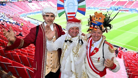 Drei kostümierte österreichische Fans vor dem Spiel im Stadion.