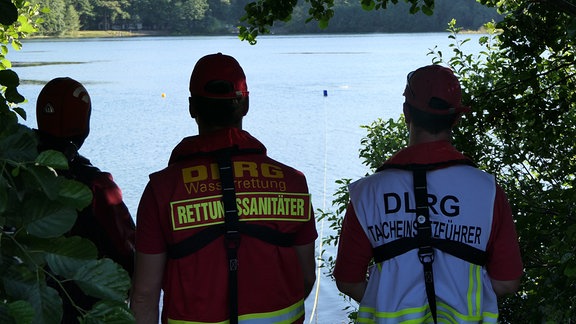 Drei Mitglieder der Deutschen Lebensrettungs gesellschaft blicken auf den Albrechtshainer See bei Leipzig.