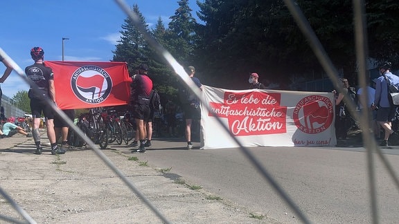 Teilnehmer einer Fahrrad-Demo halten während eines Stopps Transparente mit der Aufschrift "Antifaschistische Aktion".