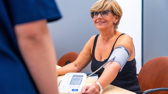 Eine Frau bekommt ihren Blutdruck mit einem Messgerät am Arm ermittelt.