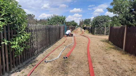 Feuerwehrschläuche auf dem Weg einer Kleingartenanlage