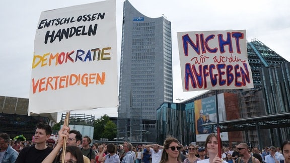 Teilnehmer einer Demonstration gegen Rechts im Vorfeld der Landtagswahl 2024 haben sich auf dem Augustusplatz versammelt und halten Plakate mit der Aufschrift "Entschlossen Handeln - Demokratie verteidigen" und "Wir werden nicht Aufgeben".