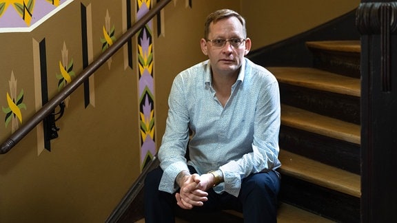 Der Schriftsteller Clemens Meyer sitzt im Treppenhaus eines Altbaus im Stadtteil Stöttertitz. 