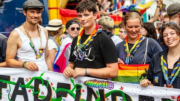 Junge Frauen und Männer sind bunt angezogen und schauen in die Kamera.