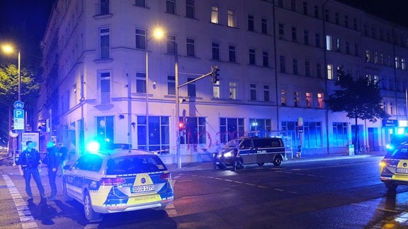 Polizeifahrzeuge stehen vor dem mit Farbe beschmierten Gebäude.