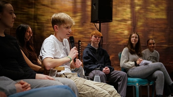 Ein Jugendlicher spricht in ein Mikrophon. 