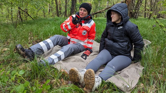 Zwei Frauen bei einem Rettungstraining im Wald. 