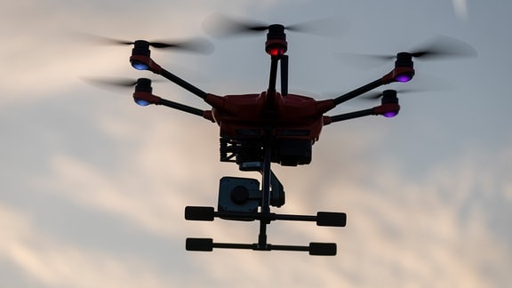 Eine Drohne, die mit einer Wärmebildkamera ausgestattet ist, schwebt am frühen Morgen über einer Wiese.
