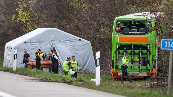 Bestatter tragen ein Todesopfer des verunglückten Busses von der Unfallstelle auf der A9.